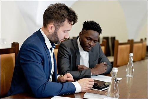 two professional adult males sitting at table reviewing documents