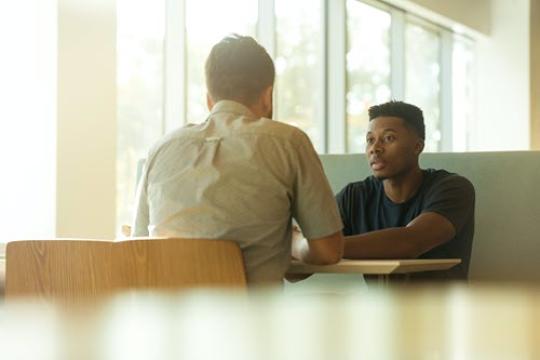 juvenile sitting at a table talking to an adult