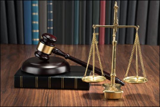 gavel on top of law book with scales of justice sitting on table