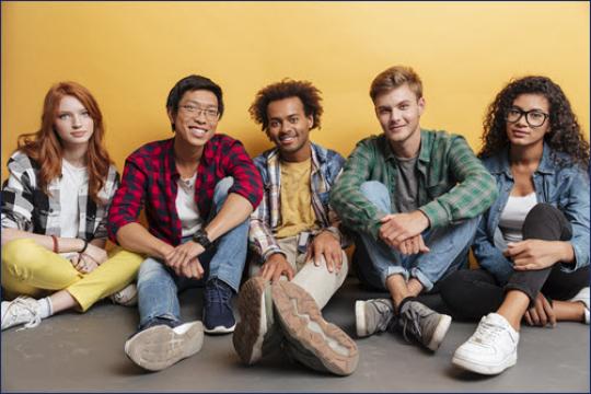 group of multi-ethnic youth sitting in front of yellow wall
